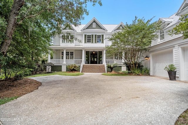 view of front of home with covered porch, driveway, a standing seam roof, a garage, and metal roof