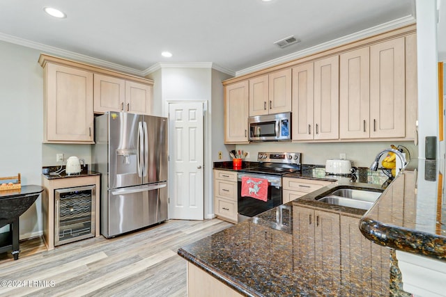 kitchen featuring sink, stainless steel appliances, wine cooler, ornamental molding, and dark stone counters