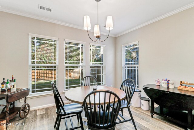 dining room with a notable chandelier, ornamental molding, a wealth of natural light, and light wood-type flooring