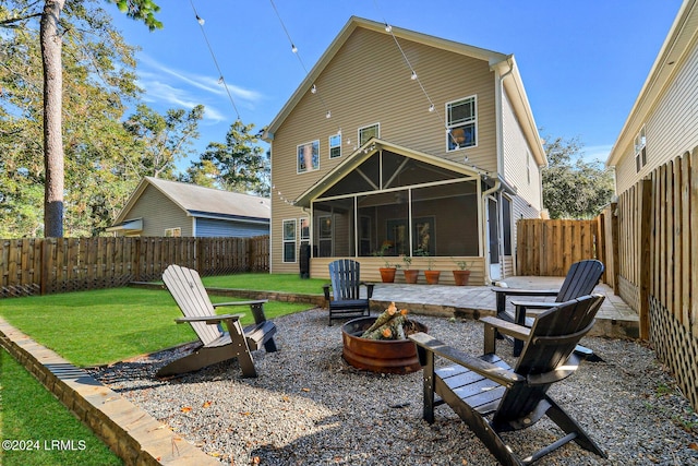 rear view of house featuring a sunroom, a fenced backyard, an outdoor fire pit, and a lawn