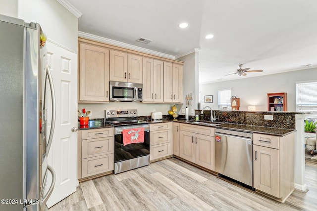 kitchen with light brown cabinetry, sink, appliances with stainless steel finishes, kitchen peninsula, and dark stone counters