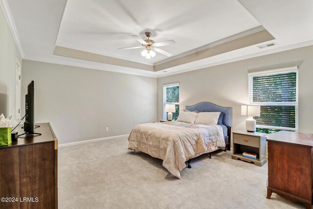 bedroom featuring multiple windows, visible vents, ornamental molding, and a tray ceiling