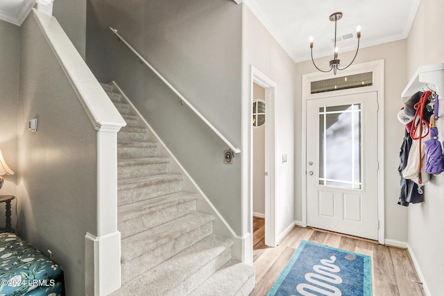 entryway with ornamental molding and light wood-type flooring