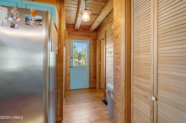 doorway to outside featuring beamed ceiling, wooden walls, light hardwood / wood-style floors, and wooden ceiling