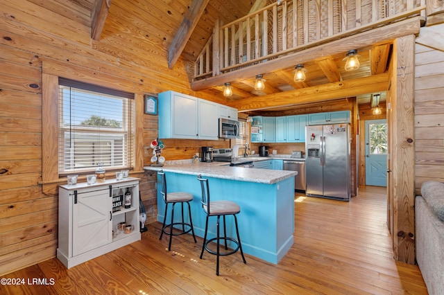 kitchen featuring a kitchen breakfast bar, wood ceiling, kitchen peninsula, stainless steel appliances, and beam ceiling