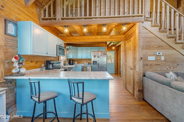 kitchen featuring stainless steel appliances, wooden ceiling, kitchen peninsula, beamed ceiling, and wood walls