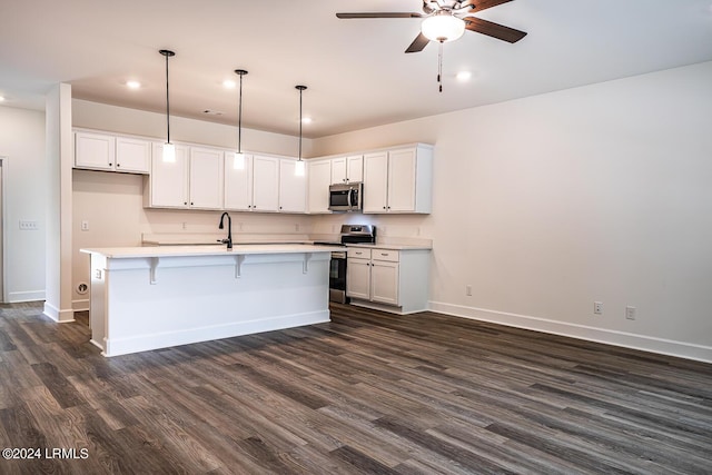 kitchen with pendant lighting, dark wood-type flooring, a kitchen island with sink, stainless steel appliances, and white cabinets