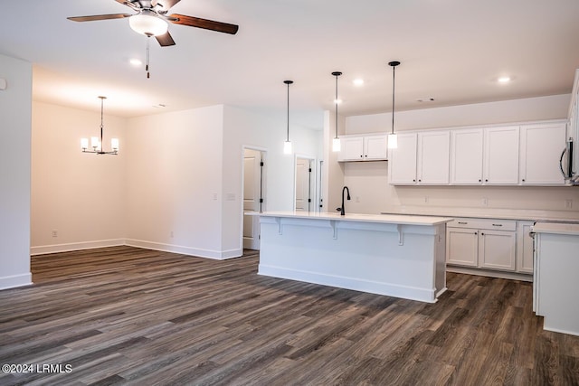 kitchen with a kitchen island with sink, white cabinetry, dark hardwood / wood-style flooring, and decorative light fixtures