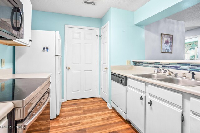 1231 Ladys Island Dr Unit 327, Port Royal, SC 29935 - kitchen with white dishwasher, black microwave, electric range, light wood-type flooring, and white cabinets