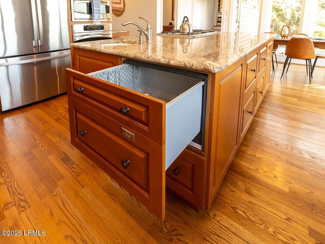 31 Hearthwood Dr, Hilton Head Island, SC 29928 - kitchen featuring light stone counters, a sink, appliances with stainless steel finishes, light wood-style flooring, and a kitchen island with sink