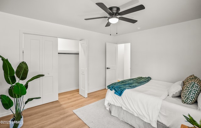 bedroom featuring a ceiling fan, light wood-type flooring, a closet, and baseboards