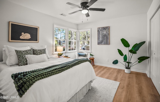 bedroom featuring visible vents, baseboards, a ceiling fan, wood finished floors, and a closet