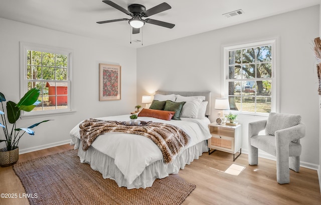 bedroom featuring light wood finished floors, baseboards, multiple windows, and visible vents