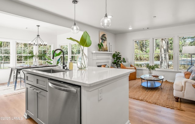 kitchen with dishwasher, open floor plan, a sink, and light wood-style floors