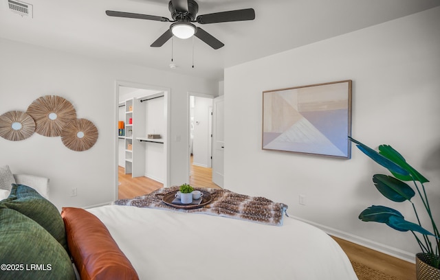 bedroom featuring visible vents, ceiling fan, baseboards, and wood finished floors