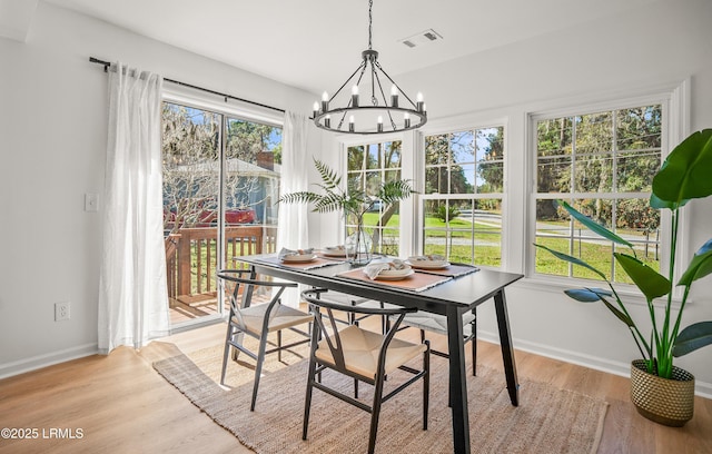 dining room featuring light wood-style floors, baseboards, visible vents, and a notable chandelier