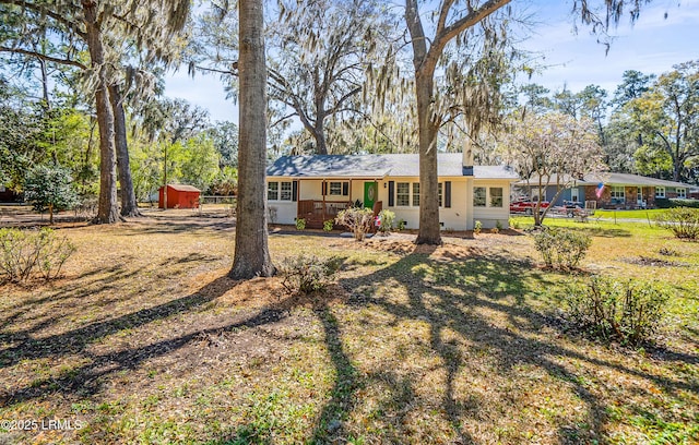 view of front of house with crawl space, fence, an outdoor structure, and a shed