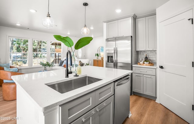 kitchen with gray cabinetry, a sink, appliances with stainless steel finishes, backsplash, and pendant lighting