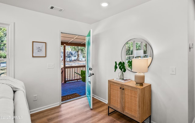 doorway with visible vents, a healthy amount of sunlight, light wood-style flooring, and baseboards