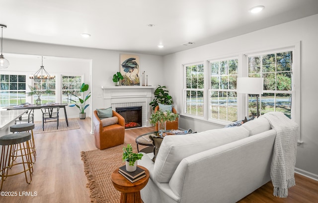 living room featuring a fireplace, wood finished floors, visible vents, and a healthy amount of sunlight