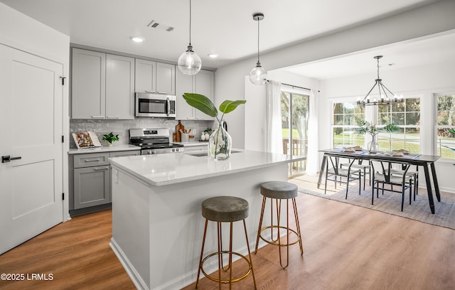 kitchen featuring stainless steel appliances, visible vents, gray cabinetry, a sink, and light wood-type flooring