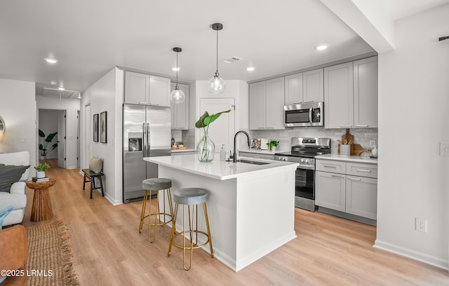 kitchen with stainless steel appliances, a breakfast bar, a sink, and light wood finished floors