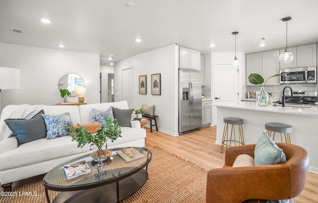 living room featuring light wood-style flooring, visible vents, baseboards, and recessed lighting