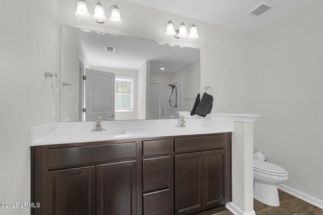 bathroom with an enclosed shower, vanity, wood-type flooring, and toilet