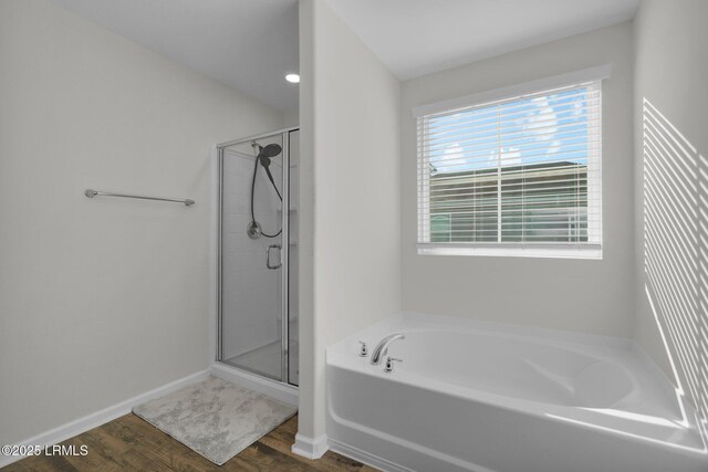 bathroom with independent shower and bath and wood-type flooring