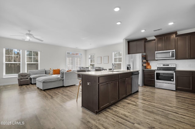 kitchen featuring a healthy amount of sunlight, decorative backsplash, appliances with stainless steel finishes, and a center island with sink