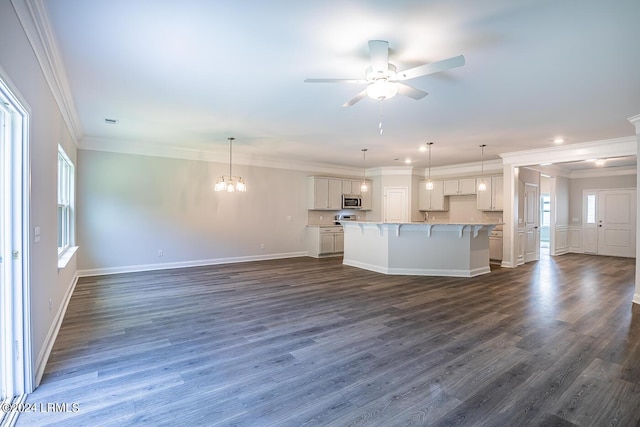 kitchen featuring dark wood-type flooring, a center island with sink, white cabinets, and decorative light fixtures