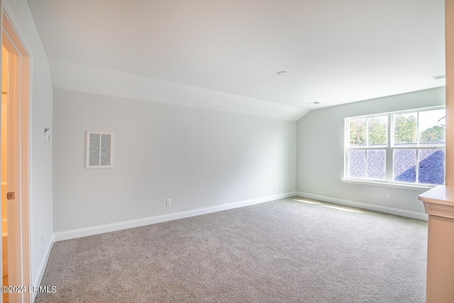 unfurnished room with vaulted ceiling and light colored carpet