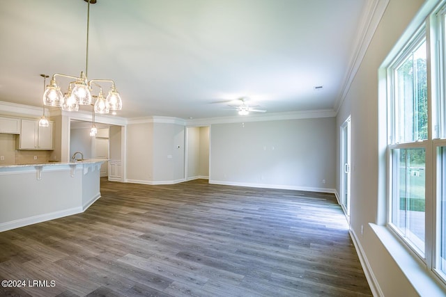 unfurnished living room with dark hardwood / wood-style flooring, ceiling fan, crown molding, and a healthy amount of sunlight