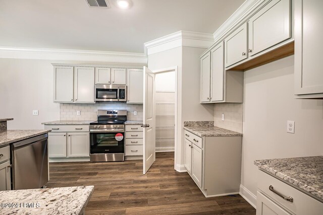 kitchen featuring white cabinetry, appliances with stainless steel finishes, dark hardwood / wood-style floors, light stone countertops, and decorative backsplash