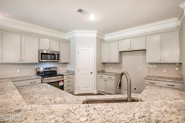 kitchen featuring sink, light stone counters, crown molding, appliances with stainless steel finishes, and backsplash