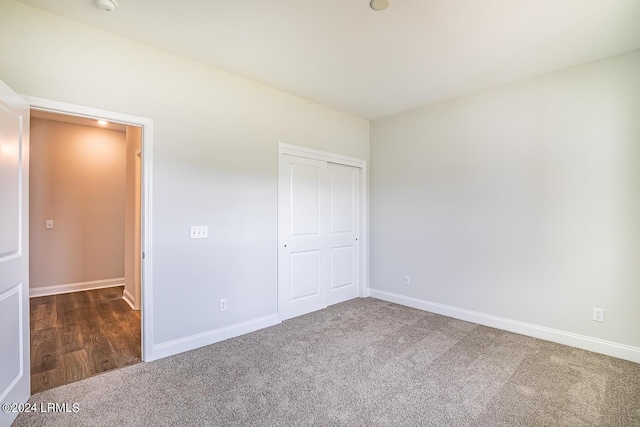 unfurnished bedroom featuring dark carpet and a closet