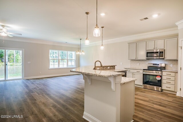 kitchen with appliances with stainless steel finishes, a breakfast bar area, hanging light fixtures, a kitchen island with sink, and a healthy amount of sunlight