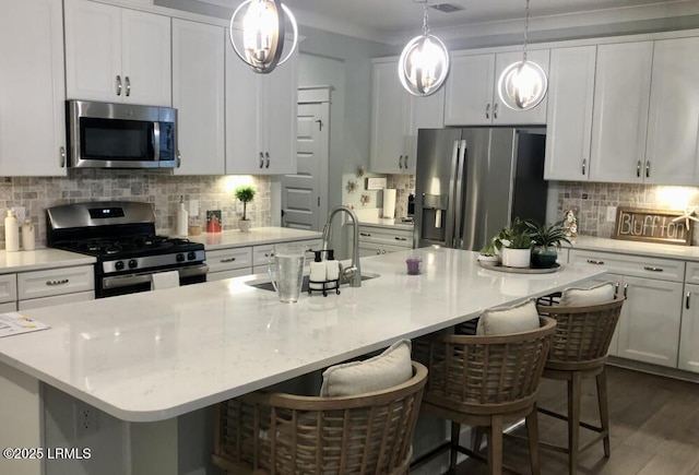 kitchen with stainless steel appliances, a breakfast bar, and a center island with sink