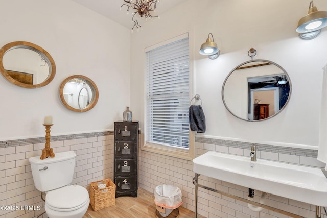 bathroom with tile walls, hardwood / wood-style flooring, and toilet