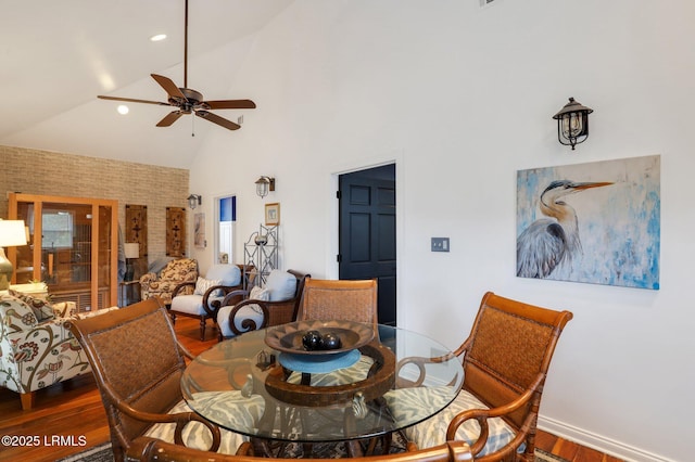 dining area with ceiling fan, high vaulted ceiling, and dark hardwood / wood-style flooring