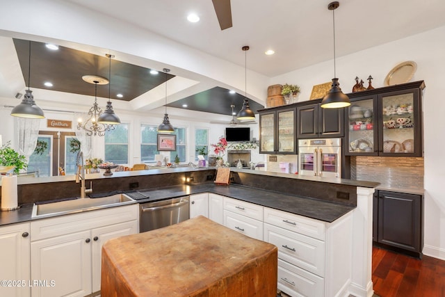 kitchen featuring sink, a center island, appliances with stainless steel finishes, pendant lighting, and white cabinets