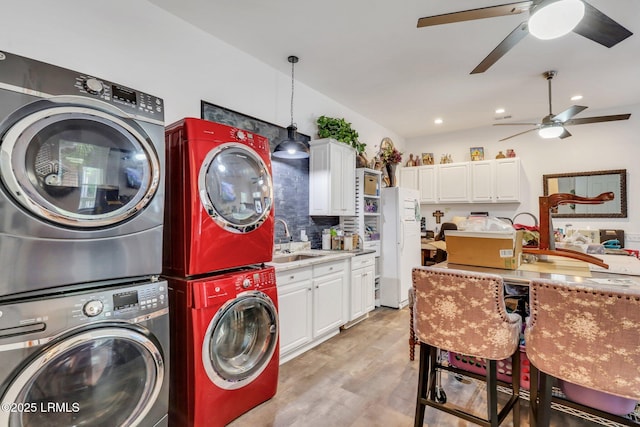 clothes washing area with ceiling fan, stacked washing maching and dryer, light hardwood / wood-style floors, and sink