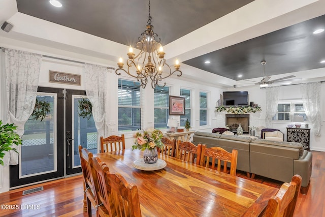 dining room with ceiling fan, a raised ceiling, and hardwood / wood-style floors