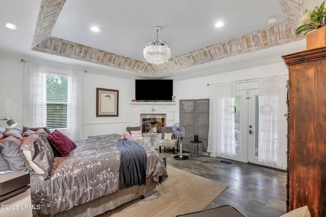 bedroom with french doors, an inviting chandelier, dark hardwood / wood-style floors, a tray ceiling, and access to exterior