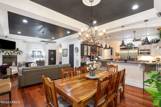 dining room featuring dark hardwood / wood-style flooring, sink, a raised ceiling, and ceiling fan