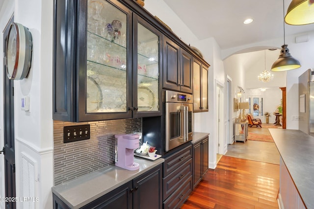 kitchen featuring stainless steel oven, a chandelier, hanging light fixtures, dark hardwood / wood-style flooring, and backsplash