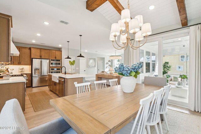 dining area with lofted ceiling with beams, a notable chandelier, and light wood-type flooring