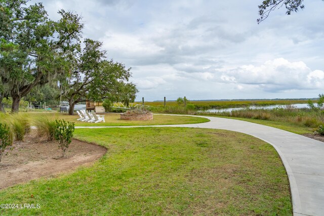 view of home's community with a water view and a lawn