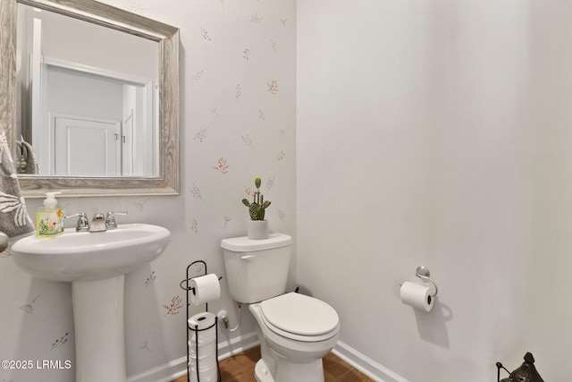 bathroom featuring baseboards, a sink, toilet, and wood finished floors