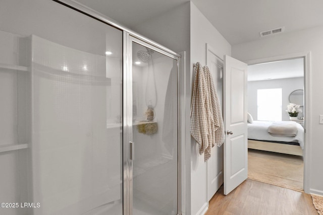 full bath with ensuite bath, visible vents, a stall shower, and wood finished floors